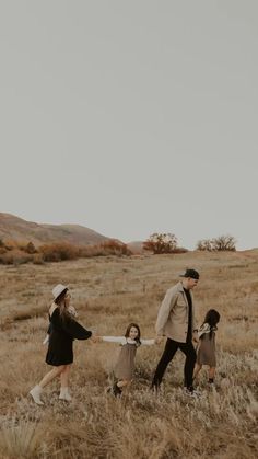 a man and two girls are walking through the grass