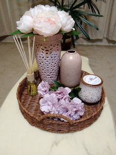 a wicker tray with vases, candles and flowers in it on a table