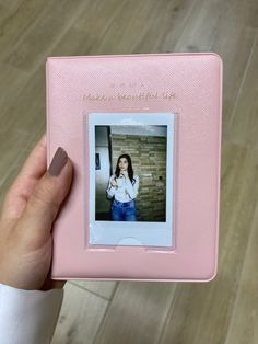 a person holding up a pink photo album