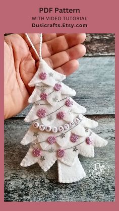 a white christmas tree ornament hanging from a string on a wooden table with text overlay