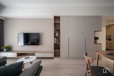 a living room filled with furniture and a flat screen tv mounted on a wall next to a wooden table