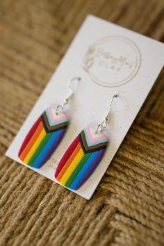 a pair of rainbow earrings sitting on top of a card