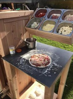 a pizza sitting on top of a wooden table next to bowls of food and drinks