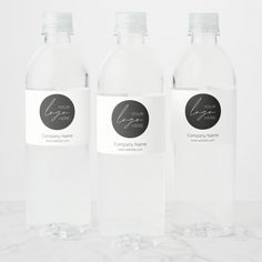 three clear water bottles with labels on them