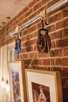 two pictures hanging on a brick wall next to a coat rack with hooks and clothes pins