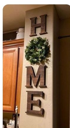 a sign that says home on the side of a kitchen wall with a wreath above it