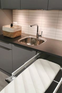 a kitchen sink sitting under a faucet next to a counter with a basket on it