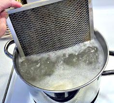 a person holding a strainer over some boiling water