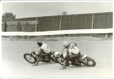 two men riding motorcycles on a track near one another in the middle of an obstacle course