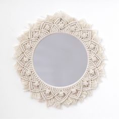 a white circular mirror with tassels on the edges and a small round mirror in the middle