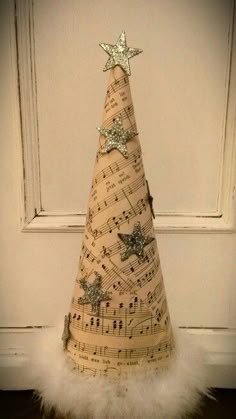 a small christmas tree made out of sheet music notes with stars on top and white fur