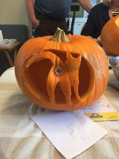 two pumpkins with faces carved into them on a table next to a man and woman