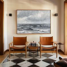 two chairs and a coffee table in front of a painting on the wall above them