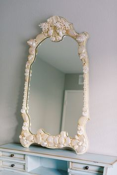 an ornate white mirror sitting on top of a dresser