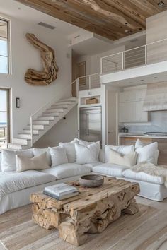 a living room filled with white furniture and lots of natural wood pieces on the floor