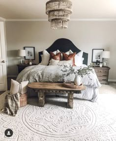 a bedroom with a large bed and chandelier hanging from the ceiling