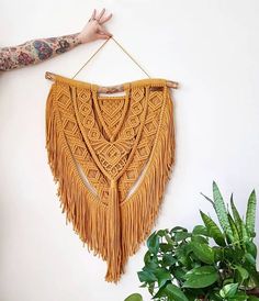 a woman's arm is holding up a wall hanging with fringes on it