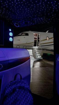 an airplane is parked in the dark with its door open and stairs lit up at night