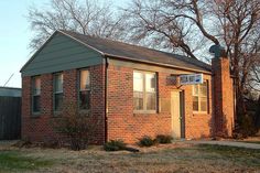 a small brick building with a sign on the front door and trees in the background