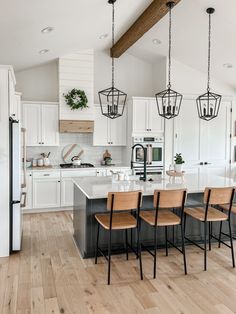 a large kitchen with white cabinets and wooden flooring, along with an island in the middle