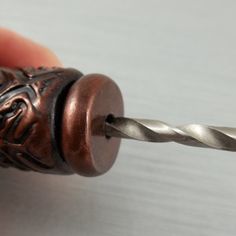 a close up of a person's hand holding a drill with a metal handle