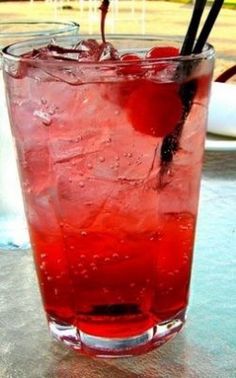 a tall glass filled with red liquid and ice