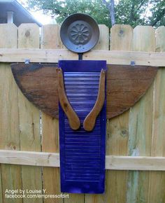 a wooden fence with a blue wall hanging on it's side and a metal object in the middle