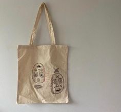 a tote bag hanging on the wall with two faces drawn on it's side