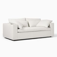 a white couch with four pillows on it's back and one arm facing the camera