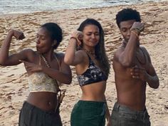 three young people standing on the beach posing for a photo with their arms in the air