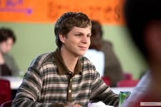 a young man sitting at a table with food in front of him and looking to the side