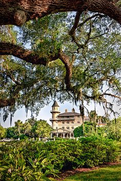 an old building with trees and bushes around it in the middle of a park area