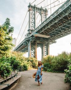 a woman in a blue dress is walking under the bridge