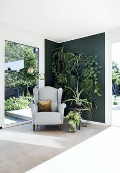 a living room with green walls and plants on the wall, along with a chair