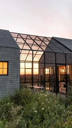 two buildings with glass windows are shown at sunset