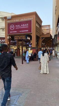 people are walking on the sidewalk in front of shops and stores at an outdoor mall