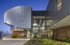 an exterior view of a modern building with glass walls and plants on the outside wall