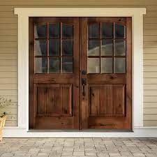 two wooden doors sitting next to each other on a brick floor in front of a house