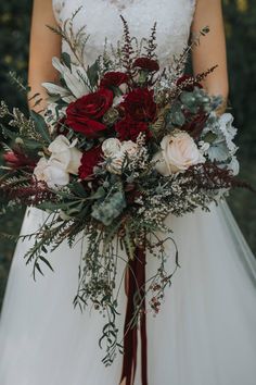 a bride holding a red and white bouquet