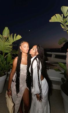 two women standing next to each other near plants