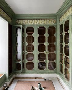 an empty room with green painted walls and glass doors on the wall, in front of a window