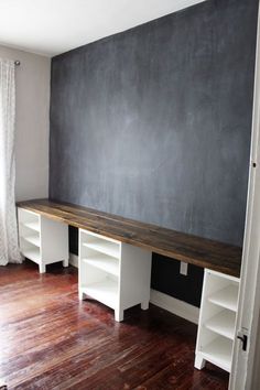 an empty room with a chalkboard on the wall and white shelves in front of it