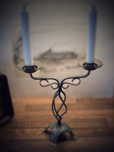 two blue candles sitting on top of a wooden table next to a candelabra