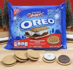 an oreo sandwich and four cookies on a wooden table next to a bag of s'mores