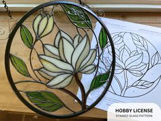 a circular stained glass window with leaves and flowers on it, hanging from a chain