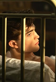 a young man in bed looking out from behind bars