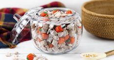 a glass jar filled with candy corn and carrots next to a bowl of candies