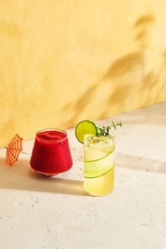 a red cup sitting on top of a white table next to a cucumber