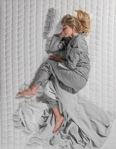 a woman laying on top of a white mattress