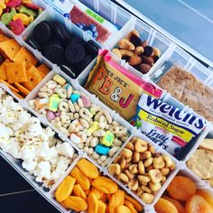 a tray filled with lots of different types of snacks and nuts in it's bins